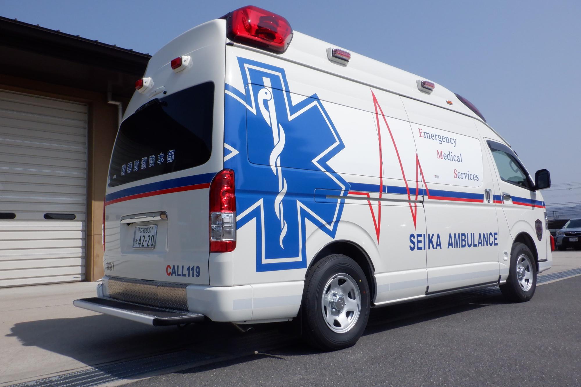 高規格救急車の運転席側と後部の写真 側面には大きなスターオブライフ、中央部に赤線及び青線がデザインがされている